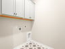 laundry room with grey and white flooring and white cabinets