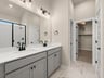 primary bath with dual sinks, grey cabinets and white flooring