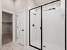 primary bathroom with shower and white flooring
