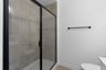 secondary bathroom with a walk-in shower with tile walls