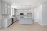 kitchen with light wood floors, light gray ceiling height cabinets, white quartz counters, and window above sink