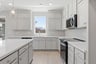 kitchen with light gray ceiling height cabinets, white counters, light wood floors, and window looking out to the backyard above sink