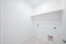 laundry room with tile floors and white shelf