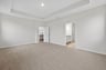 primary bedroom with carpet and tray ceiling