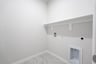 laundry room with tile floors and white shelf