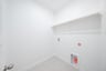 laundry room with tile floors and white shelf