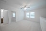 open loft with carpet, window, and ceiling fan