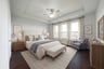 spacious primary bedroom with tray ceiling and carpet
