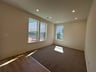 recreation room with three windows and carpet