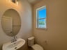 powder room with an oval mirror and a window