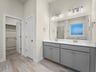 primary bathroom with dual sinks, gray cabinets and brown flooring