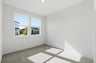 bedroom with tan carpet, white walls, and two windows looking out to front yard