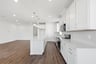 kitchen with wood floors, white cabinets, white counters, and three silver pendant lights above island