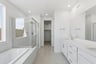 bathroom with white cabinets, white quartz counters, light tan tile floor, walk-in shower, and window above tub
