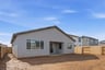 back exterior of single-story gray home with unfinished backyard and wood fence