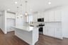 kitchen with white cabinets, white quartz counters, island, wood floors, and window above sink