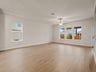 great room with brown flooring, windows, ceiling fan