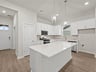 kitchen with white cabinets, brown flooring, pendant lighting and quartz countertops