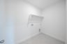 laundry room with tile floors and white shelf