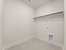 laundry room with beige flooring and white storage space