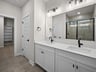 bathroom with dual sinks, quartz countertops & a walk-in shower