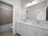 bathroom with dual sinks, quartz countertops & a bathtub
