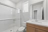 bathroom with light wood cabinets, white counter, walk-in shower, and window above toilet