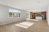 great room with light wood floors, white walls, recessed ceiling lights, and large window looking out to the backyard