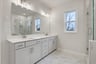 primary bathroom with white cabinets and tile flooring