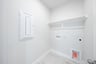 laundry room with tile floors and white shelf