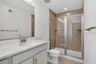 primary bath with dual vanities and a large shower