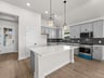kitchen with quartz countertops, brown flooring and pendant lighting