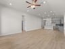 great room with brown flooring, windows and a ceiling fan