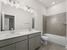 secondary bathroom with brown flooring, dual sinks and a soaking tub