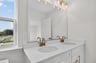 dual vanity in the primary bathroom with lighting sconces above mirror