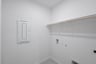laundry room with tile floors and white shelf