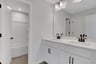 secondary bathroom with white cabinets and tile flooring
