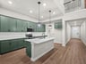 kitchen with brown flooring, green cabinets, and quartz countertops 