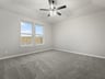 primary bedroom with carpet, dual windows, ceiling fan and a sloped ceiling 
