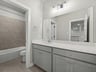 secondary bathroom with grey cabinets, white countertops and soaking tub