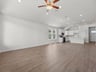 great room with brown flooring, ceiling fan, and sloped ceiling