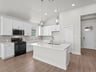 kitchen with quartz countertops, brown flooring and pendant lighting