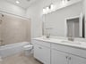 secondary bathroom with soaking tub, dual sinks and beige flooring 