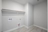 laundry room with tile floors and white shelf