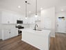 kitchen with white cabinets, quartz countertops & pendant lighting