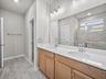 bathroom with dual sinks, quartz countertops & a walk-in shower