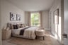 bedroom with tan area rug under light gray upholstered bed, round wood nightstands, and window