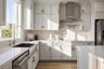 kitchen with white cabinets & counters, wood floors, and window over large farmhouse sink