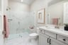 bathroom with white cabinets and counters, large walk-in shower with white quartz surrounds and frameless glass enclosure, and pink towels
