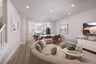 great room with wood floors, crescent shaped tan sofa, television on wall, and round light wood coffee table
